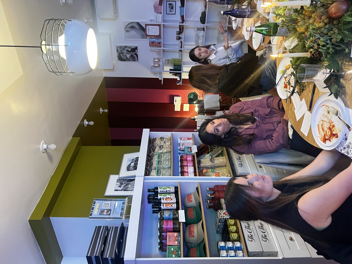 Side view of The Aperitivo Shop with shelves, signage, and founders mid-conversation