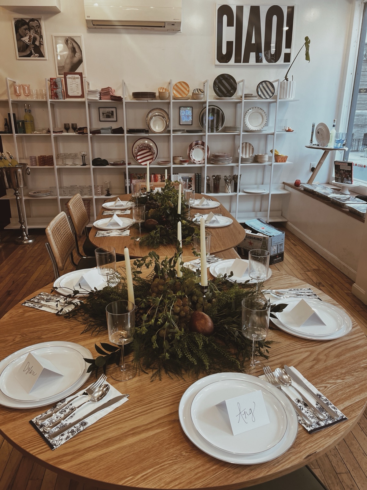 Long oval table set with greenery, candles, place cards, and a CIAO! sign